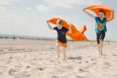 jongens met oranje handoeken rennen over het strand high rgb 6716